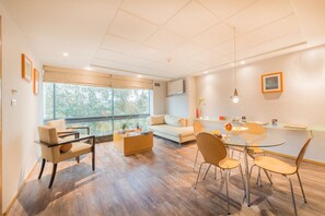 A modern living room with a sofa, chairs, a coffee table, and a dining area with a glass table and chairs. - Suites Contempo (Mexico City)