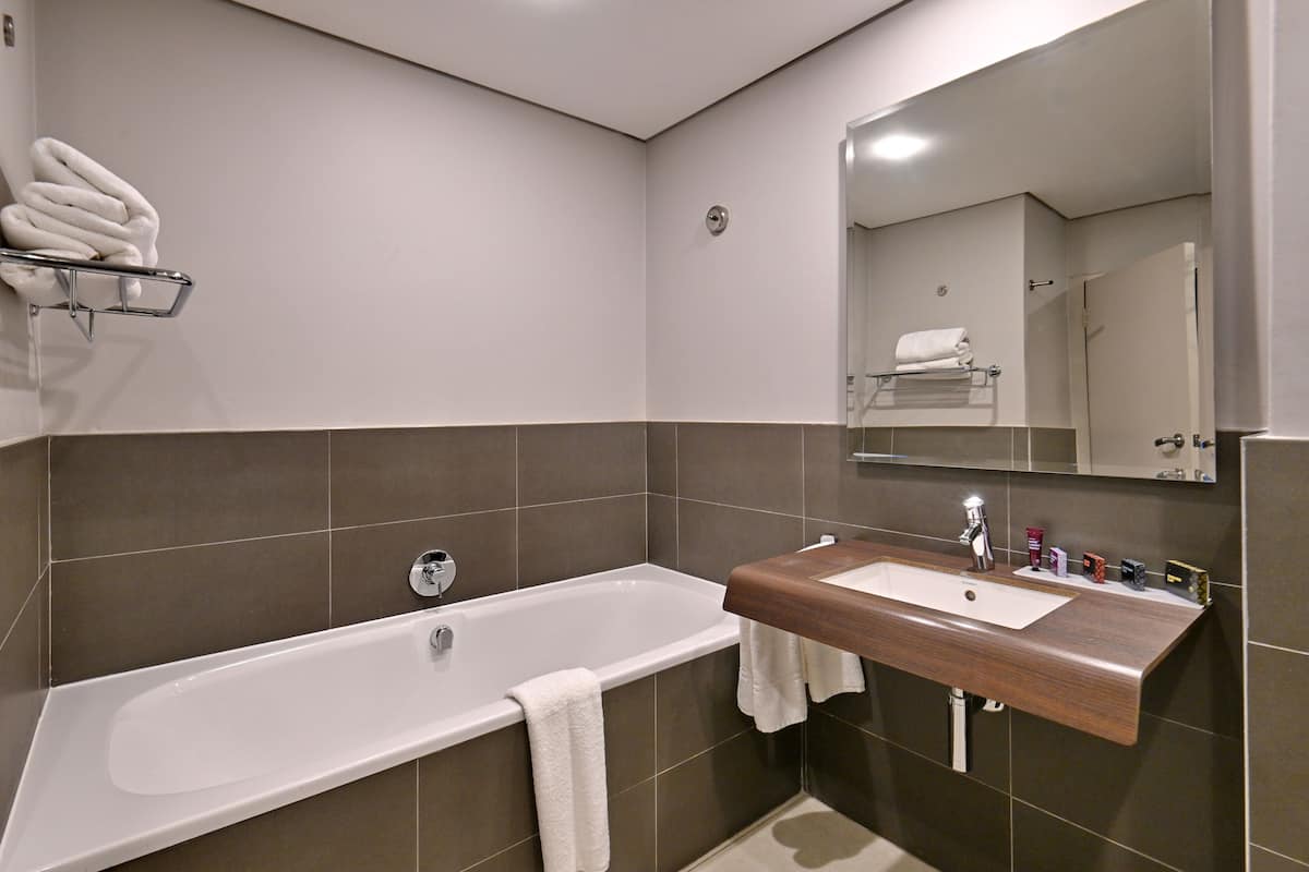 Une salle de bain moderne avec une baignoire, un meuble-lavabo en bois et un grand miroir.