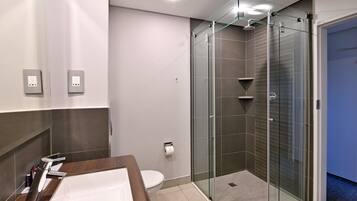 Une salle de bain moderne avec une douche à parois de verre, un meuble-lavabo en bois et des toilettes.