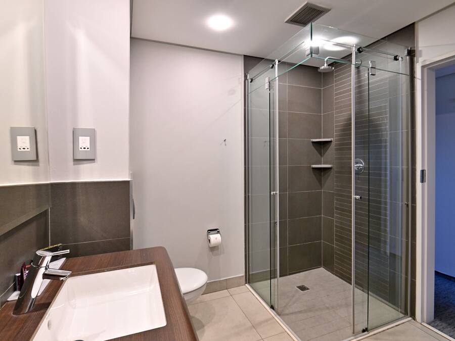 Une salle de bain moderne avec une douche à parois de verre, un meuble-lavabo en bois et des toilettes.