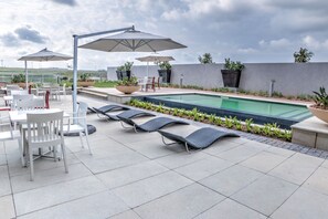A rooftop pool area with lounge chairs, umbrellas, and a dining setup. - City Lodge Hotel Waterfall City (Midrand)