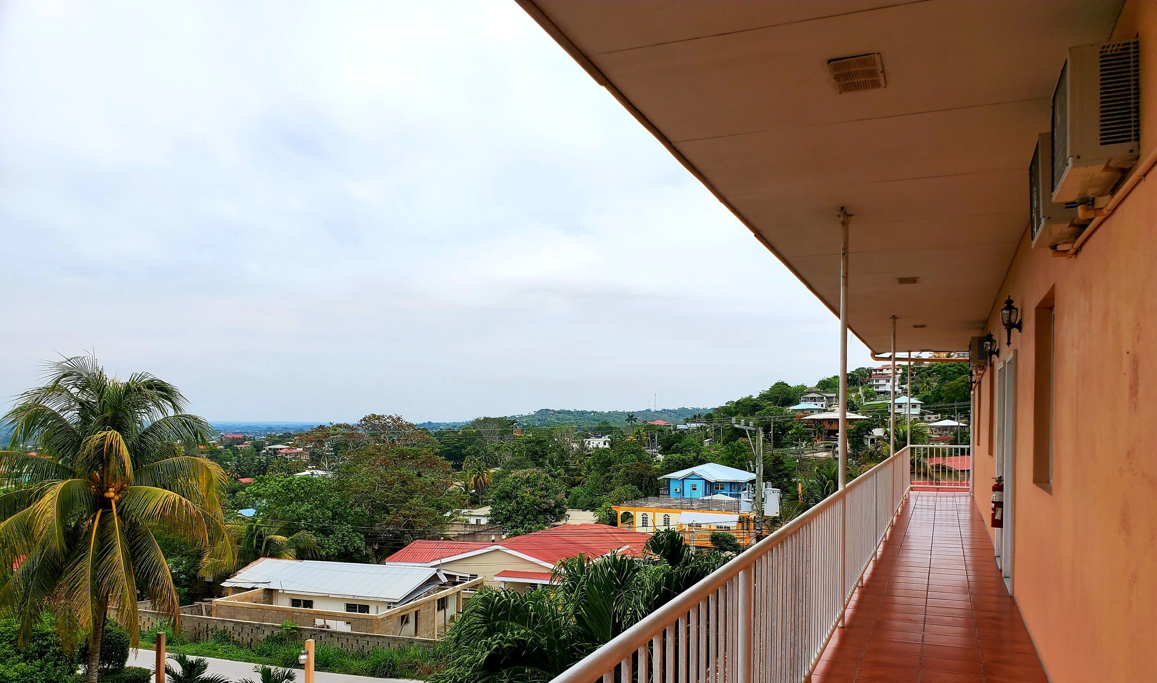 Un balcon donnant sur un quartier résidentiel, avec vue sur des maisons et des espaces verts.