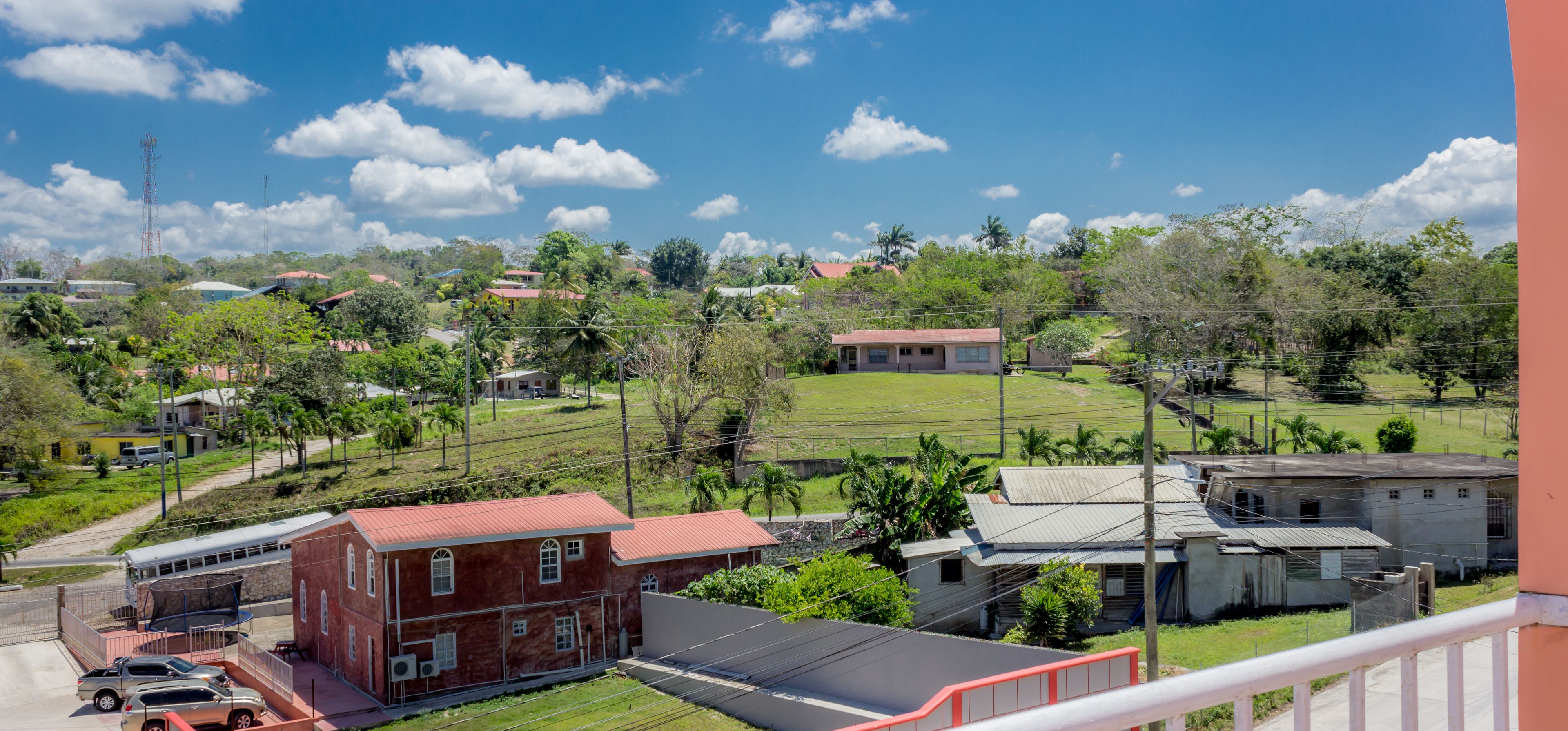 A residential area with houses, a red brick building, and a green field.