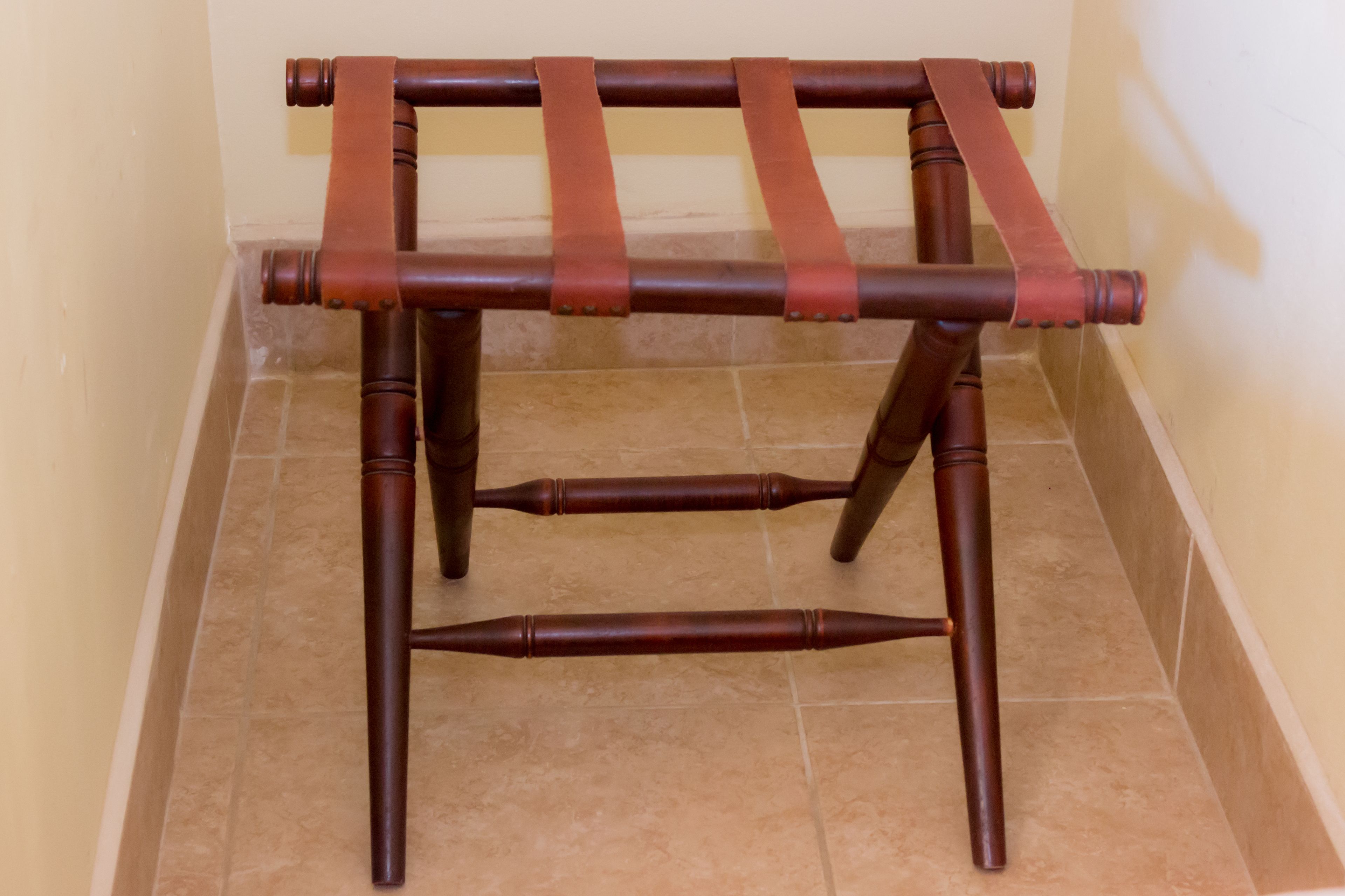 Una silla de madera con respaldo y reposabrazos, con correas de cuero.