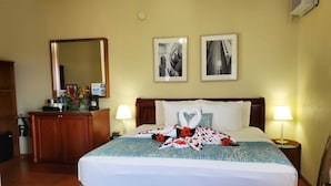 Une chambre d’hôtel avec un lit, des lampes de chevet, une commode, un miroir et deux tableaux encadrés au mur.