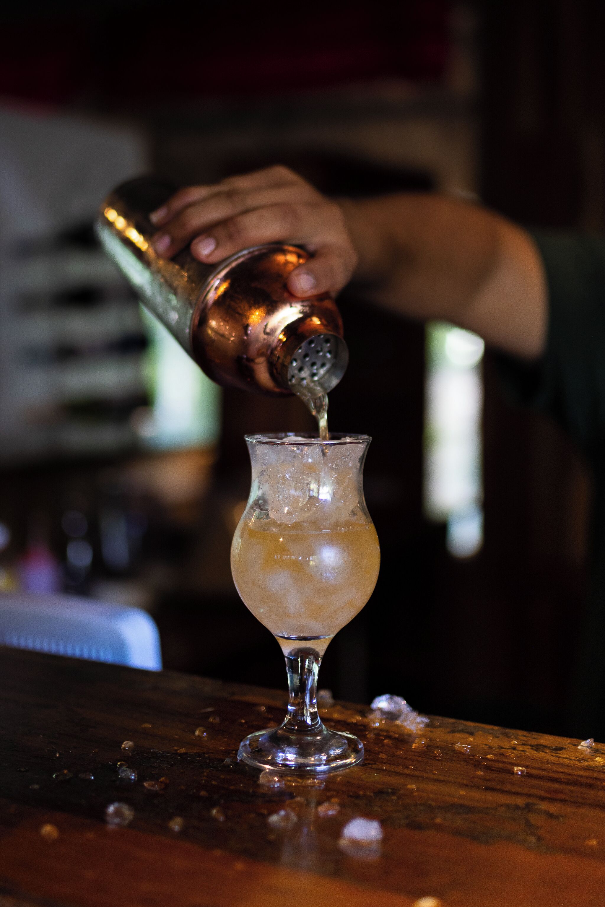 A bartender pouring a drink into a glass.