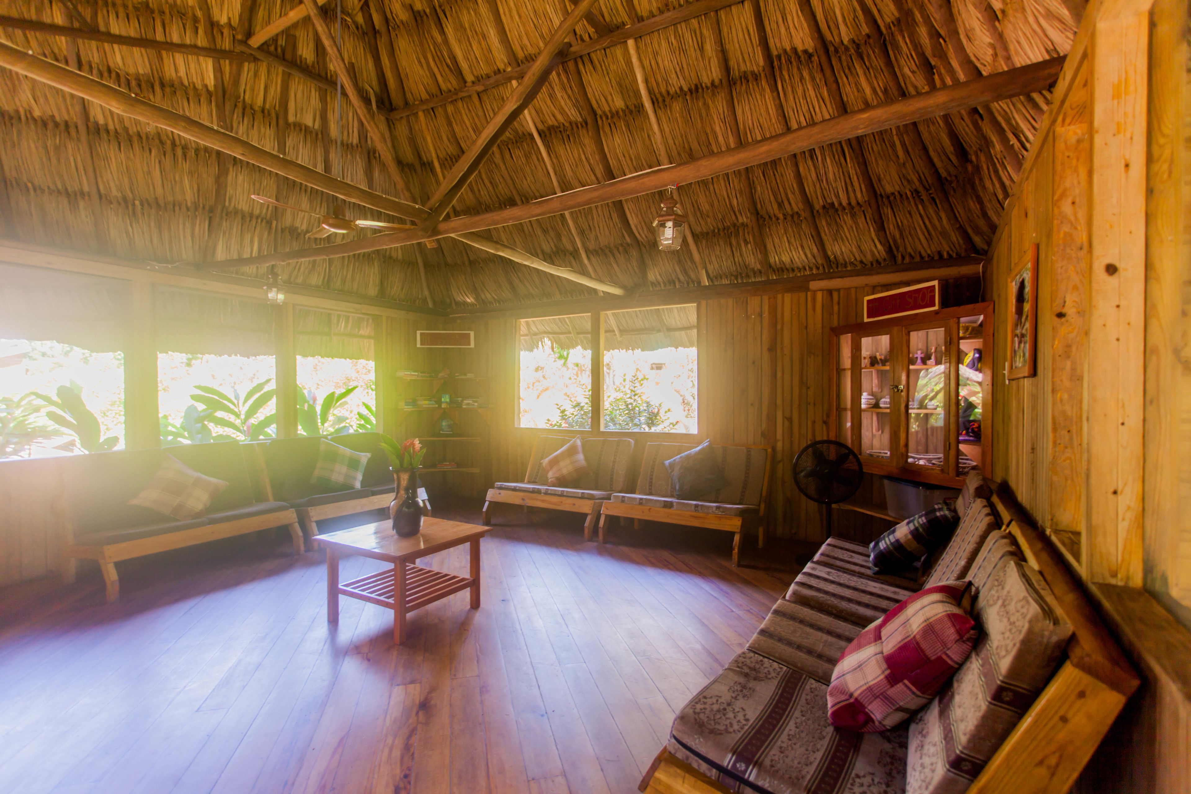 Una habitación con techo de paja, muebles de madera y ventanas amplias.