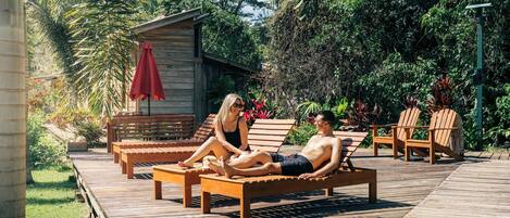 A wooden deck with lounge chairs and a small wooden structure with a red umbrella.