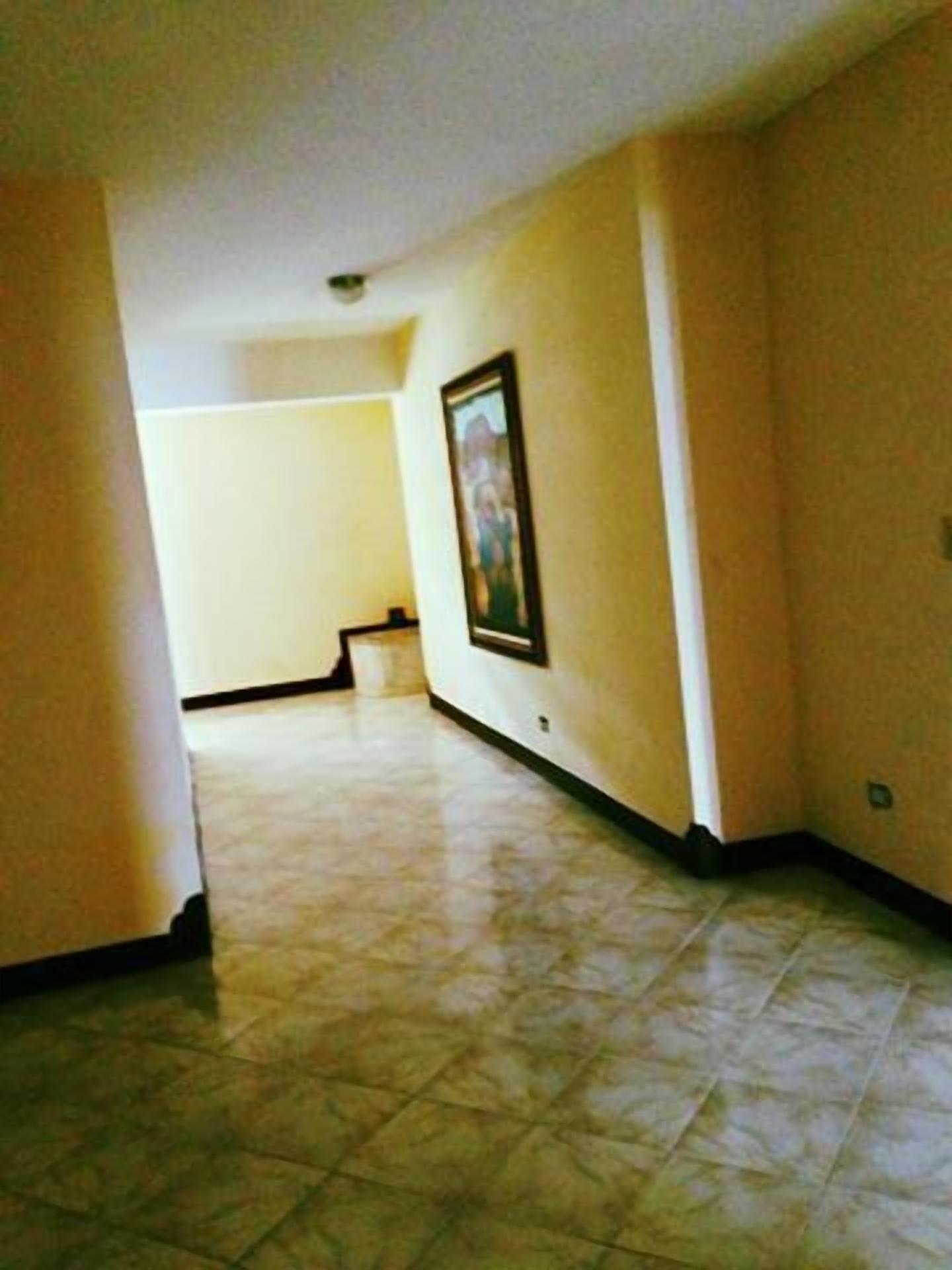 A hallway with tiled flooring and a framed picture on the wall.