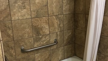 A bathroom with a bathtub, a shower curtain, and a grab bar.