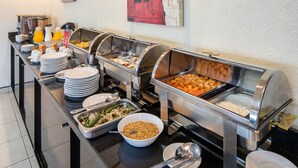 Un buffet proposant une variété de plats et d'ustensiles.