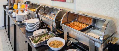 Una mesa de buffet con diversos alimentos y utensilios.