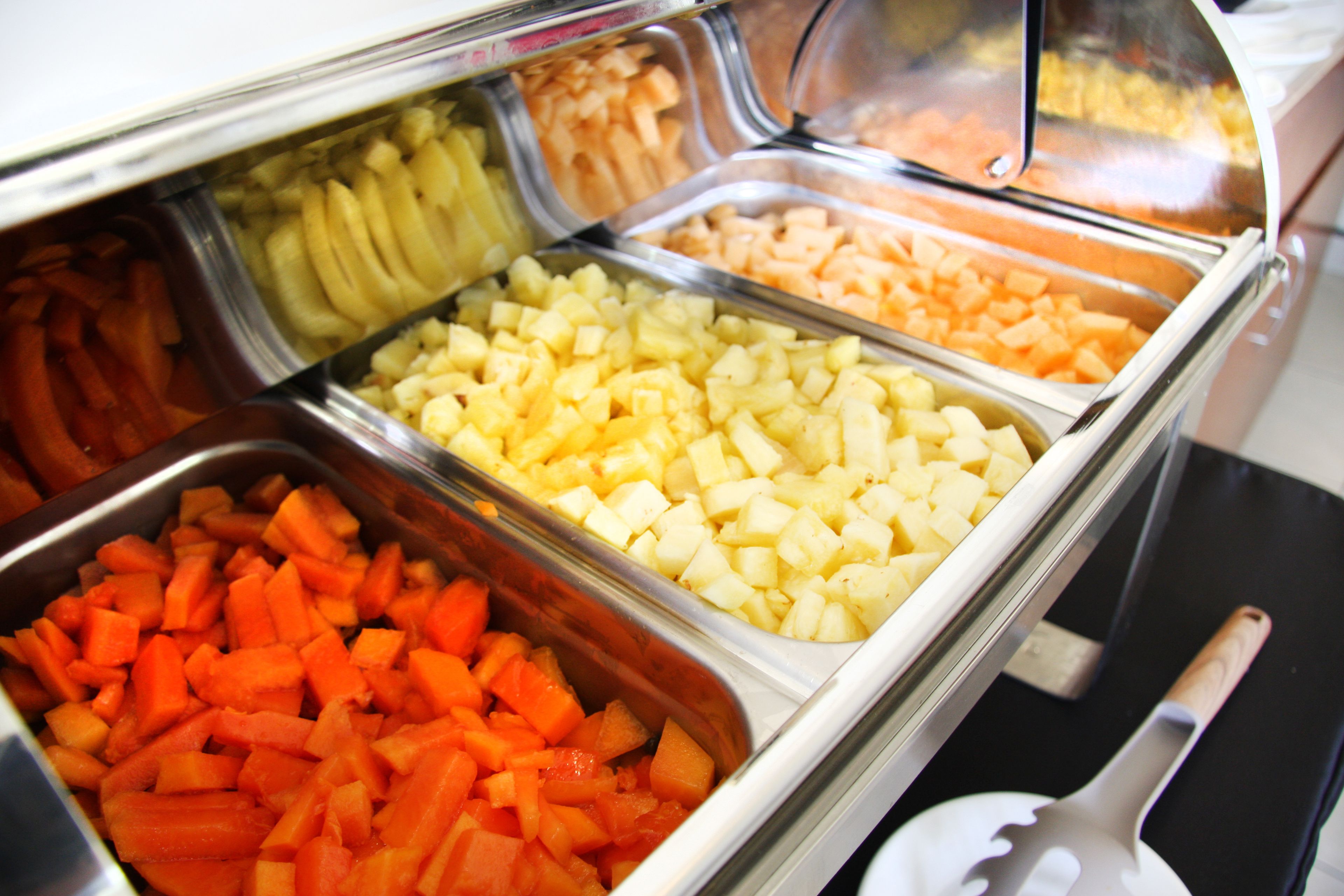 Buffet com frutas e legumes variados em recipientes de metal.