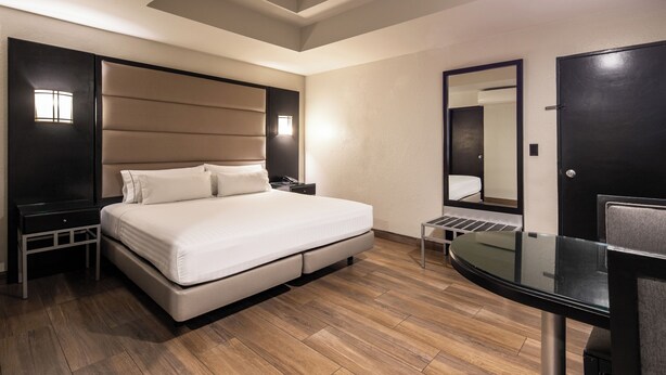 Une chambre d’hôtel moderne avec un grand lit, un bureau avec une chaise, un miroir et une petite table.