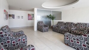 Un espace d’attente moderne, doté de canapés à motifs, d’une grande fenêtre et d’œuvres d’art accrochées aux murs.