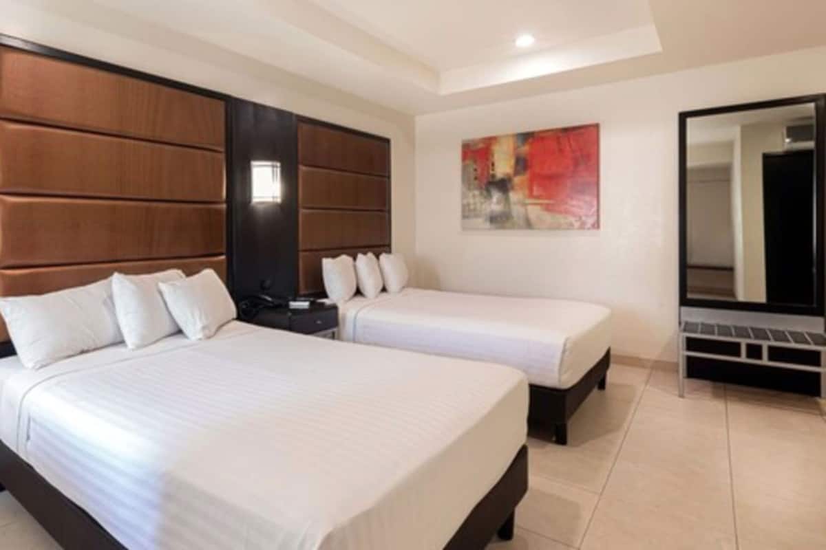 A hotel room with two beds, a large mirror, and a painting on the wall.