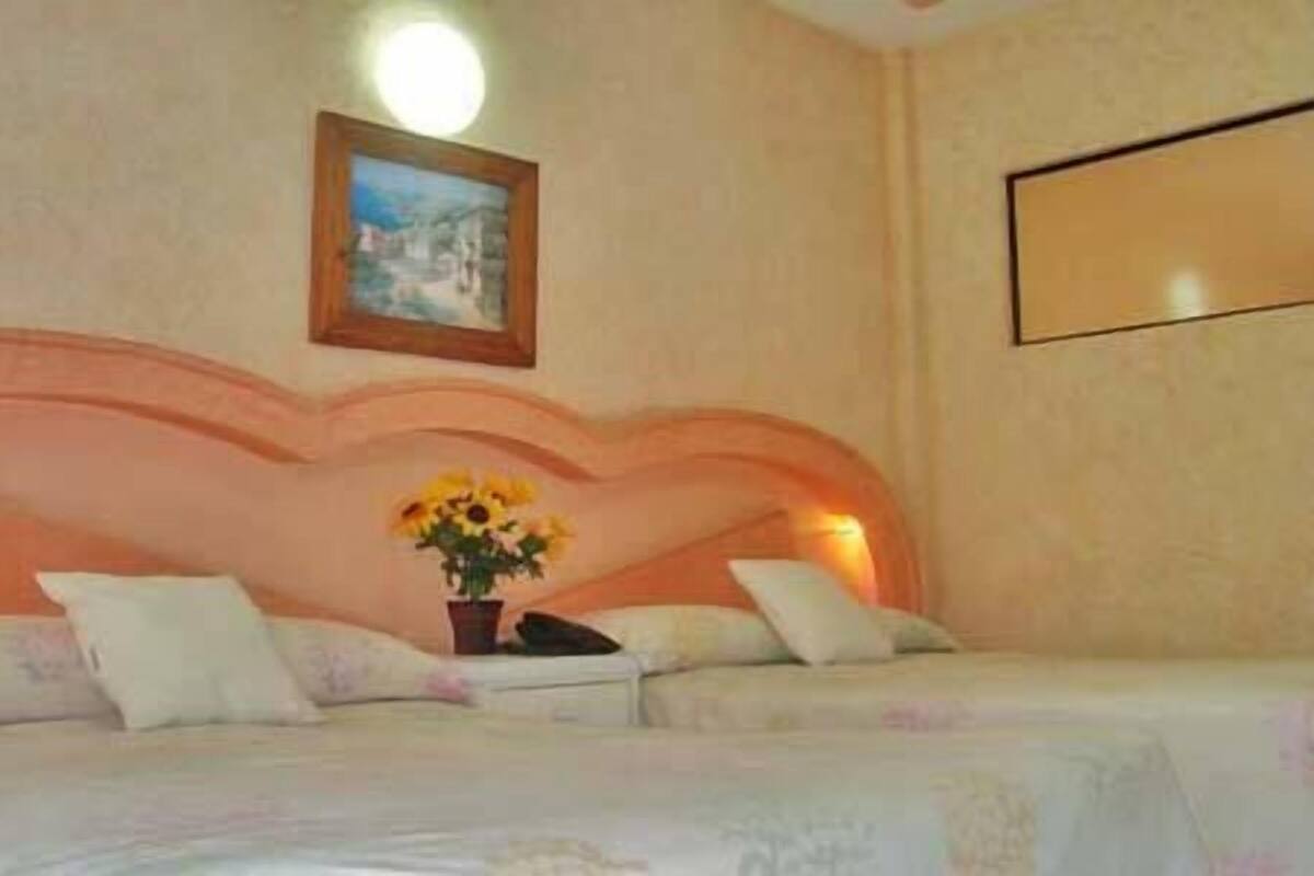 A hotel room with a bed, a nightstand, and a painting on the wall.