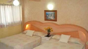 A hotel room with two beds, a nightstand, a framed picture on the wall, and a ceiling fan.