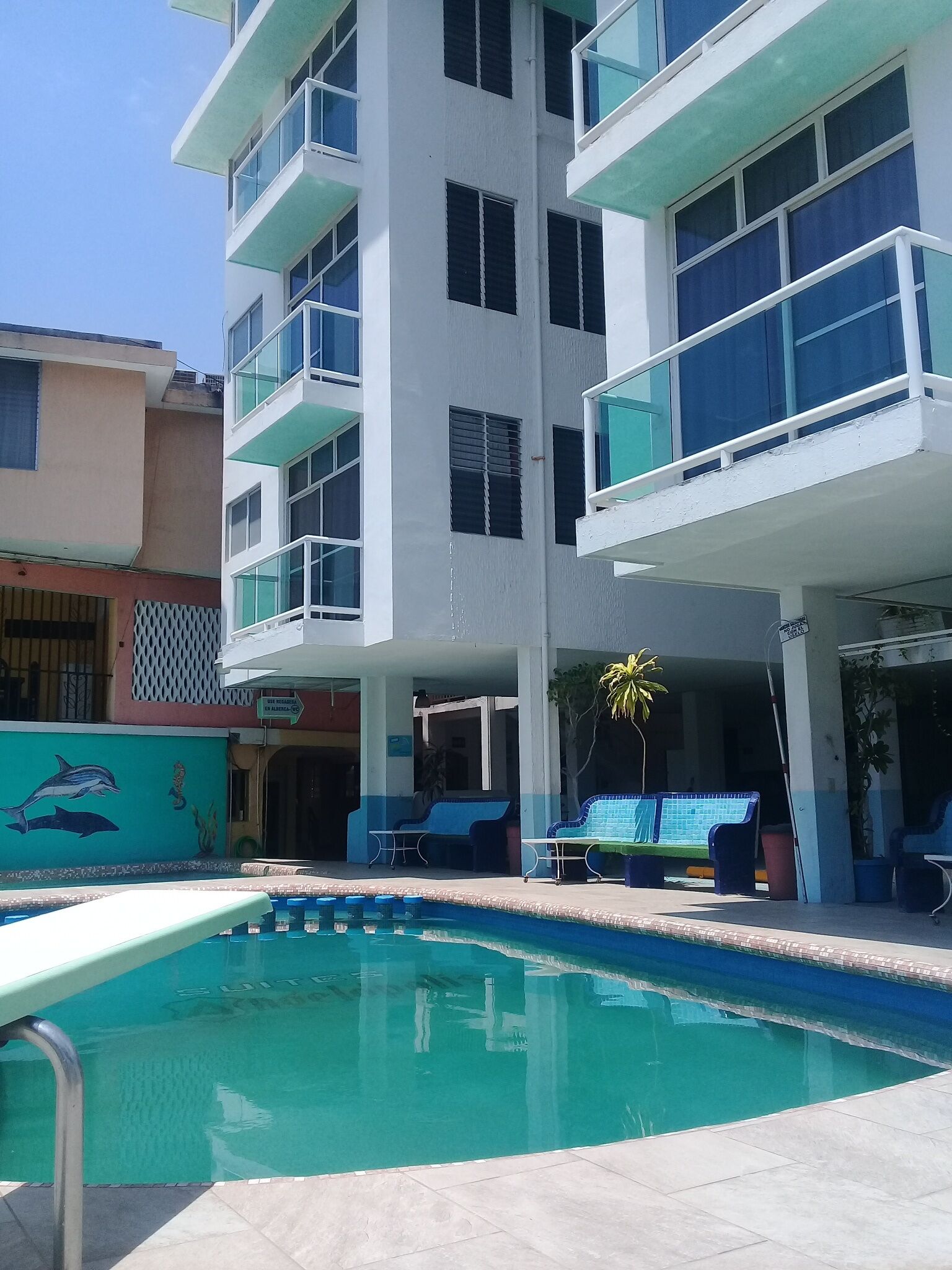 Un edificio moderno con piscina, zona de estar exterior y un mural de vida marina.