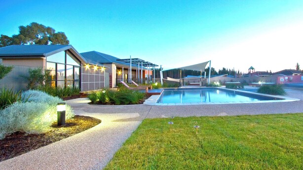 A modern house with a swimming pool, a covered outdoor area, and a well-maintained garden.