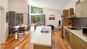 A modern kitchen with a central island, wooden cabinets, and a dining area with a round table and chairs.