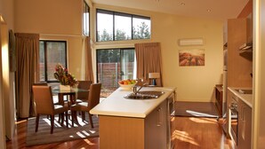A modern kitchen with a central island, wooden flooring, and large windows.