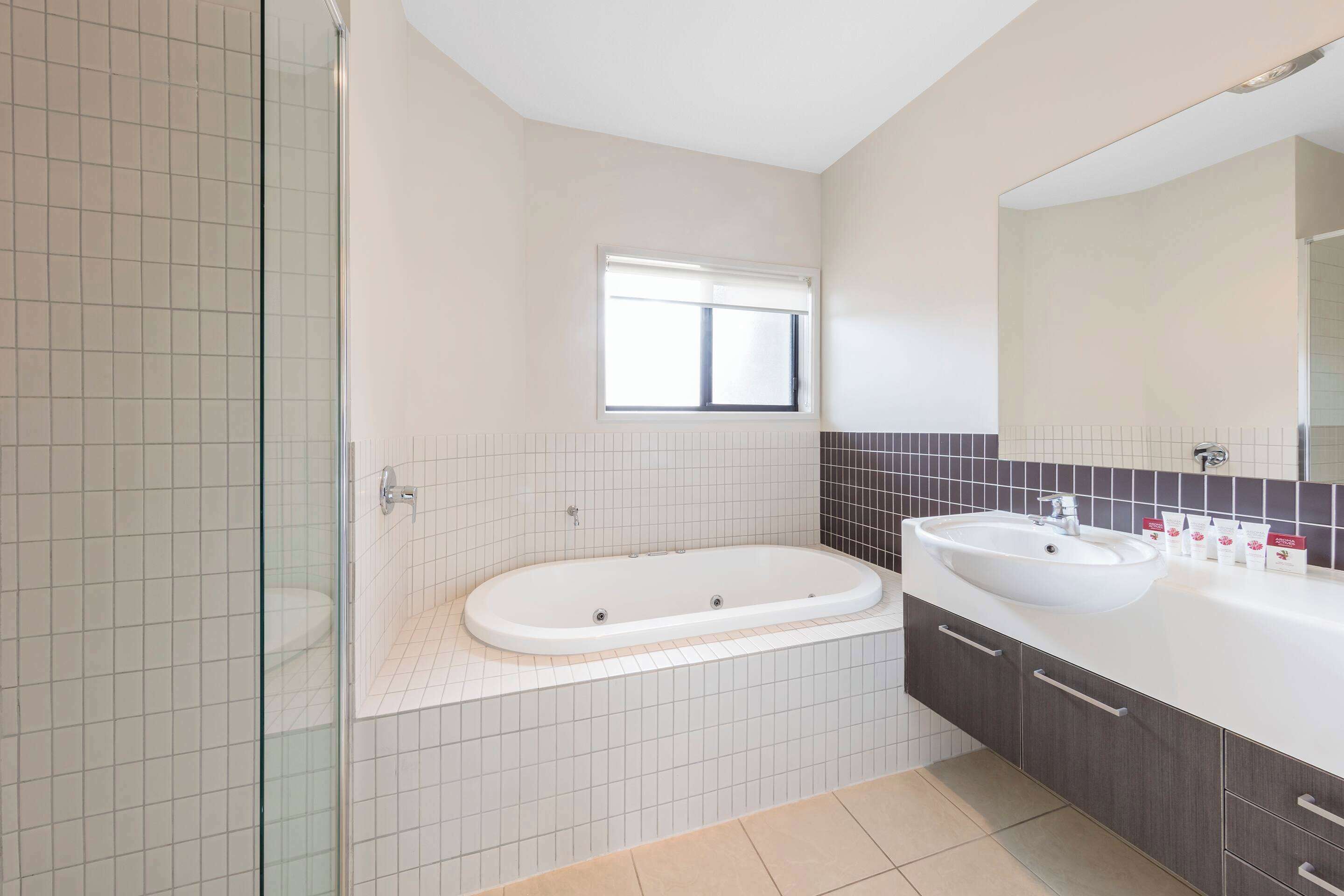 Een moderne badkamer met een douchecabine van glas, een vrijstaand bad en een wastafel met een grote spiegel.