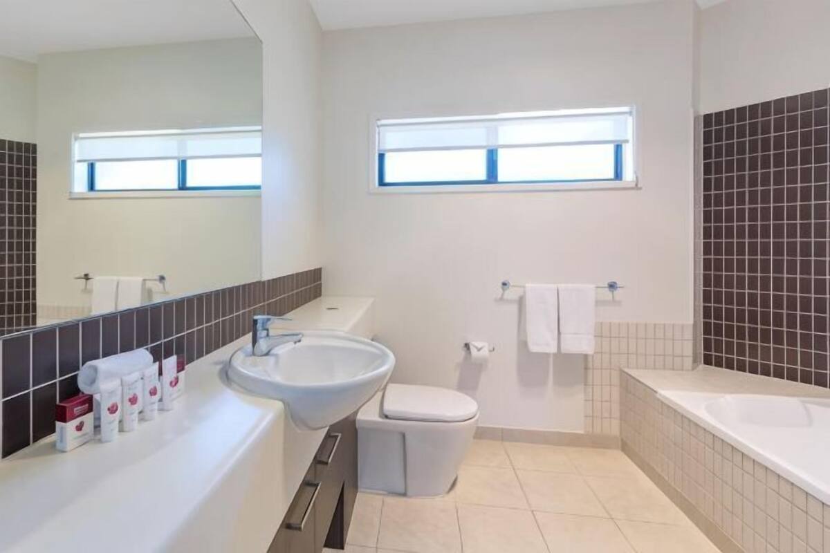 Ein Badezimmer mit Waschbecken, Toilette und Badewanne, einem Fenster und einem Spiegel.