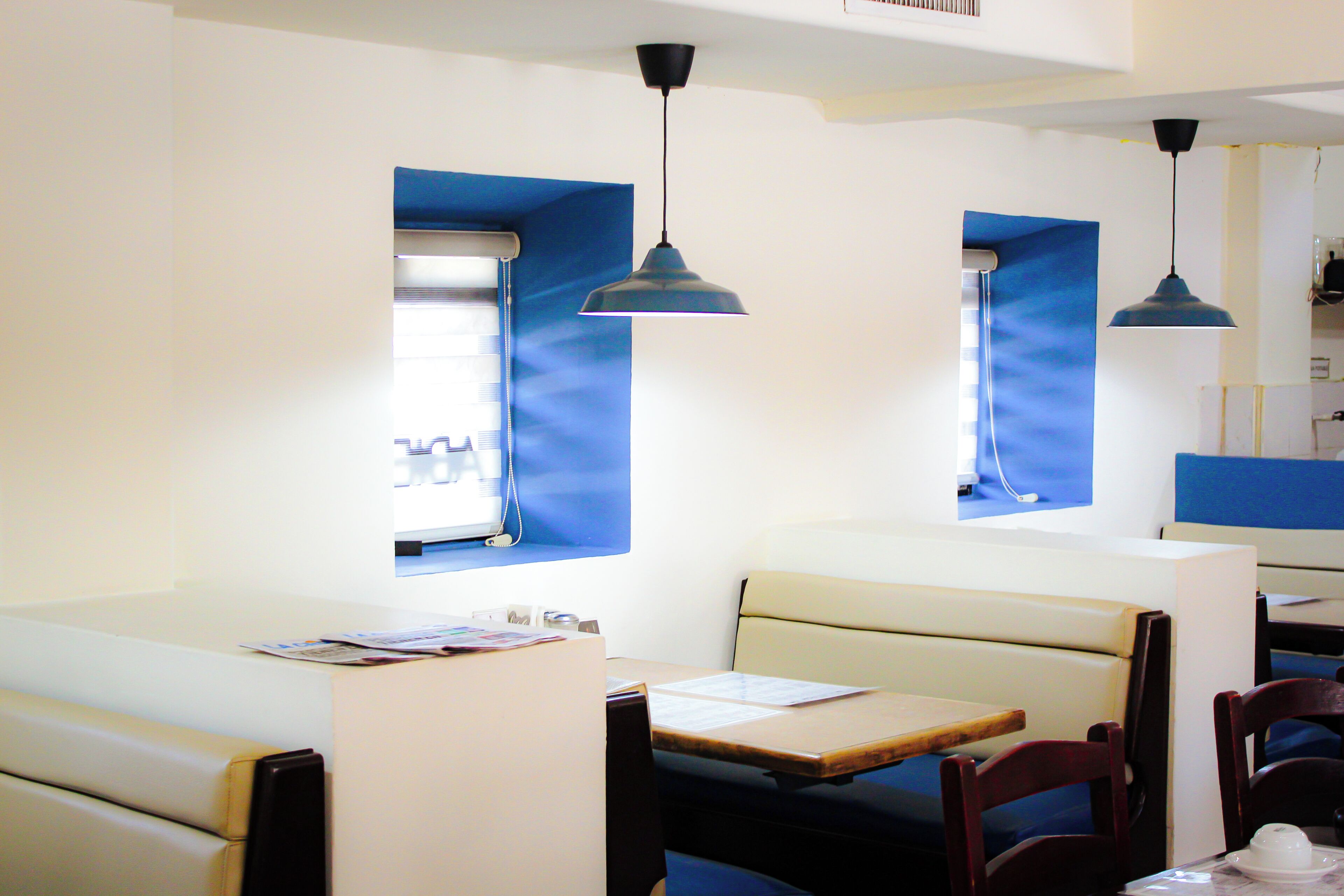Interior de restaurante com cabines, mesas e iluminação pendente.