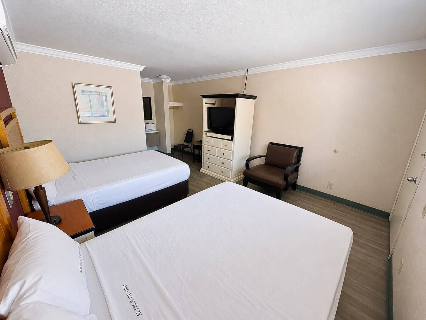 Una habitación de hotel con dos camas, un televisor, una silla y un escritorio.