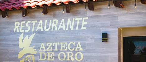 Letrero de restaurante con el nombre 'RESTAURANTE AZTECA DE ORO' y un logotipo estilizado de un águila.
