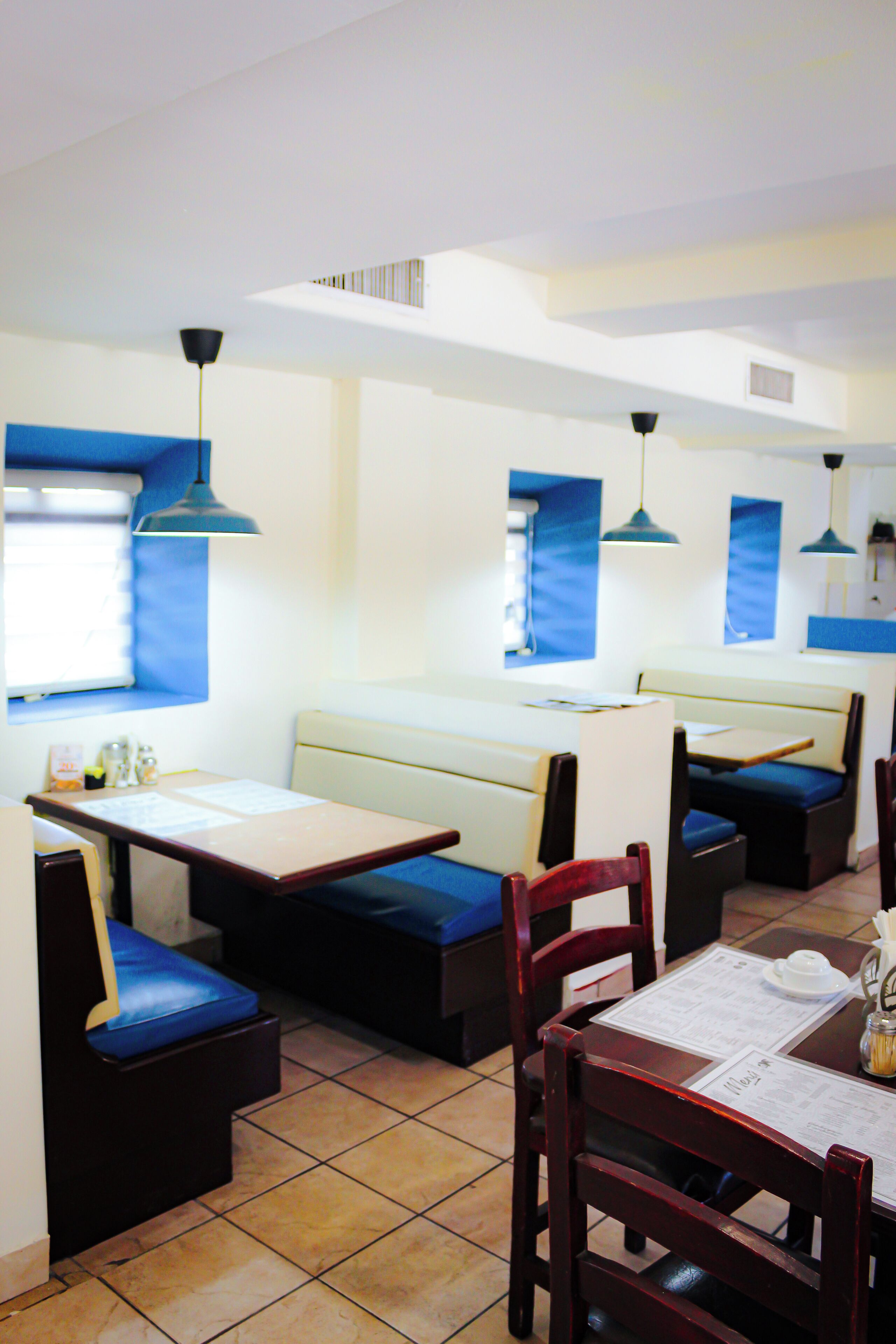 A restaurant interior with booths, tables, and blue pendant lighting.