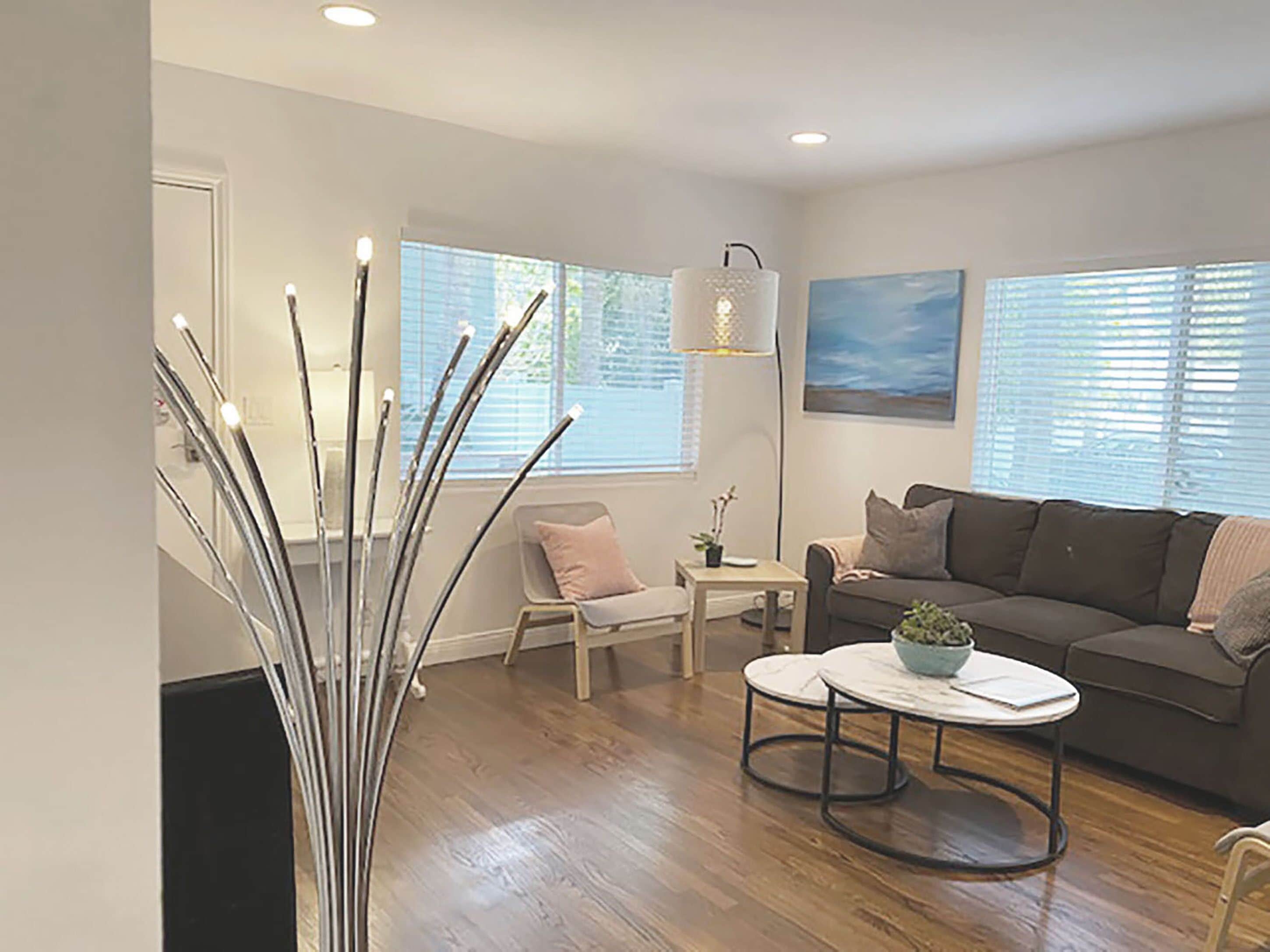 A modern living room with a wooden floor, a white sofa, a round coffee table, and a floor lamp.