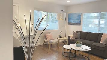 A modern living room with a wooden floor, a white sofa, a round coffee table, and a floor lamp.