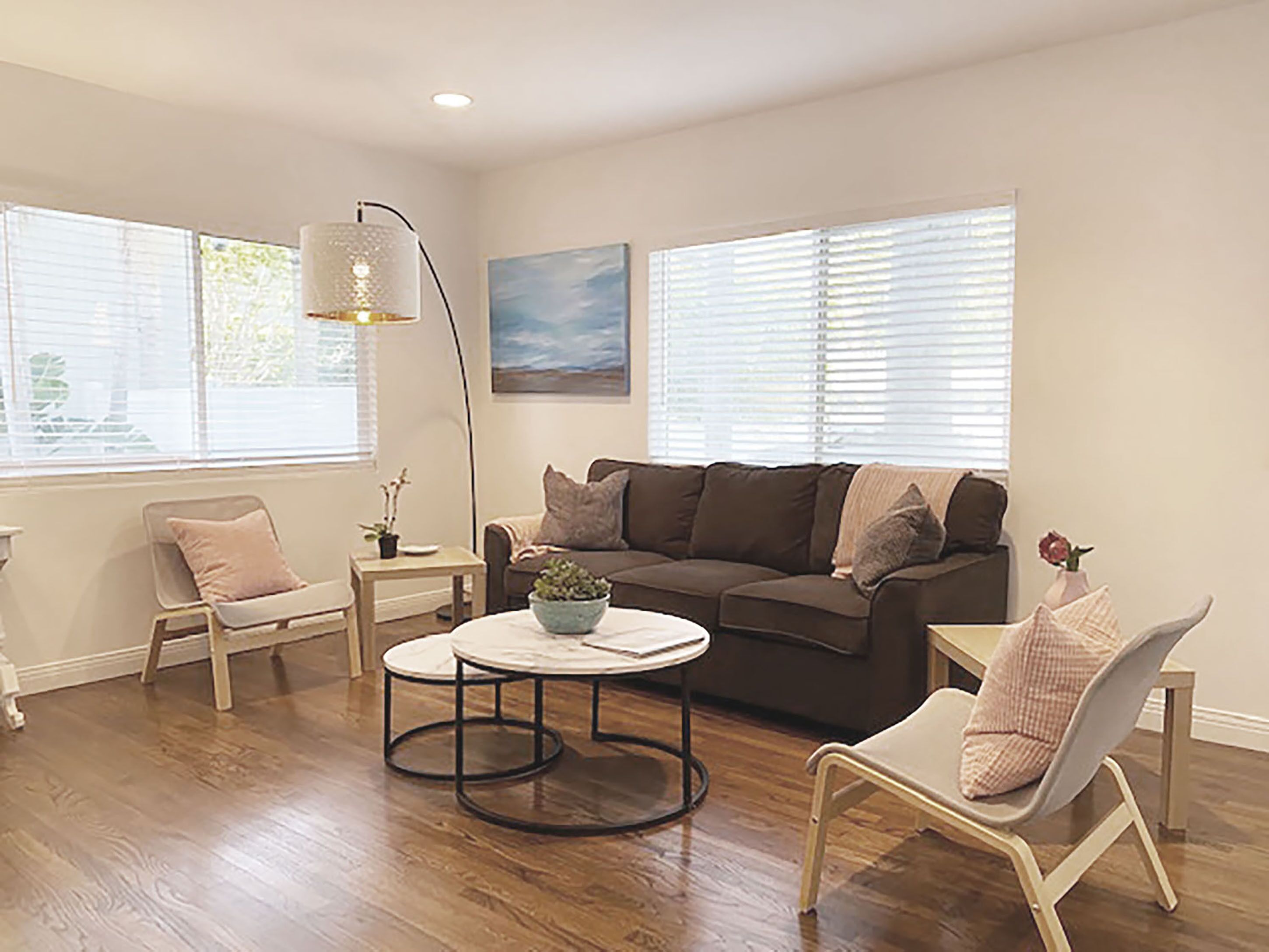 A living room with a brown sofa, two armchairs, a coffee table, and a floor lamp.