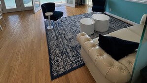 Un salon spacieux avec vue sur l’océan, une grande fenêtre, un canapé, une table basse et un téléviseur.