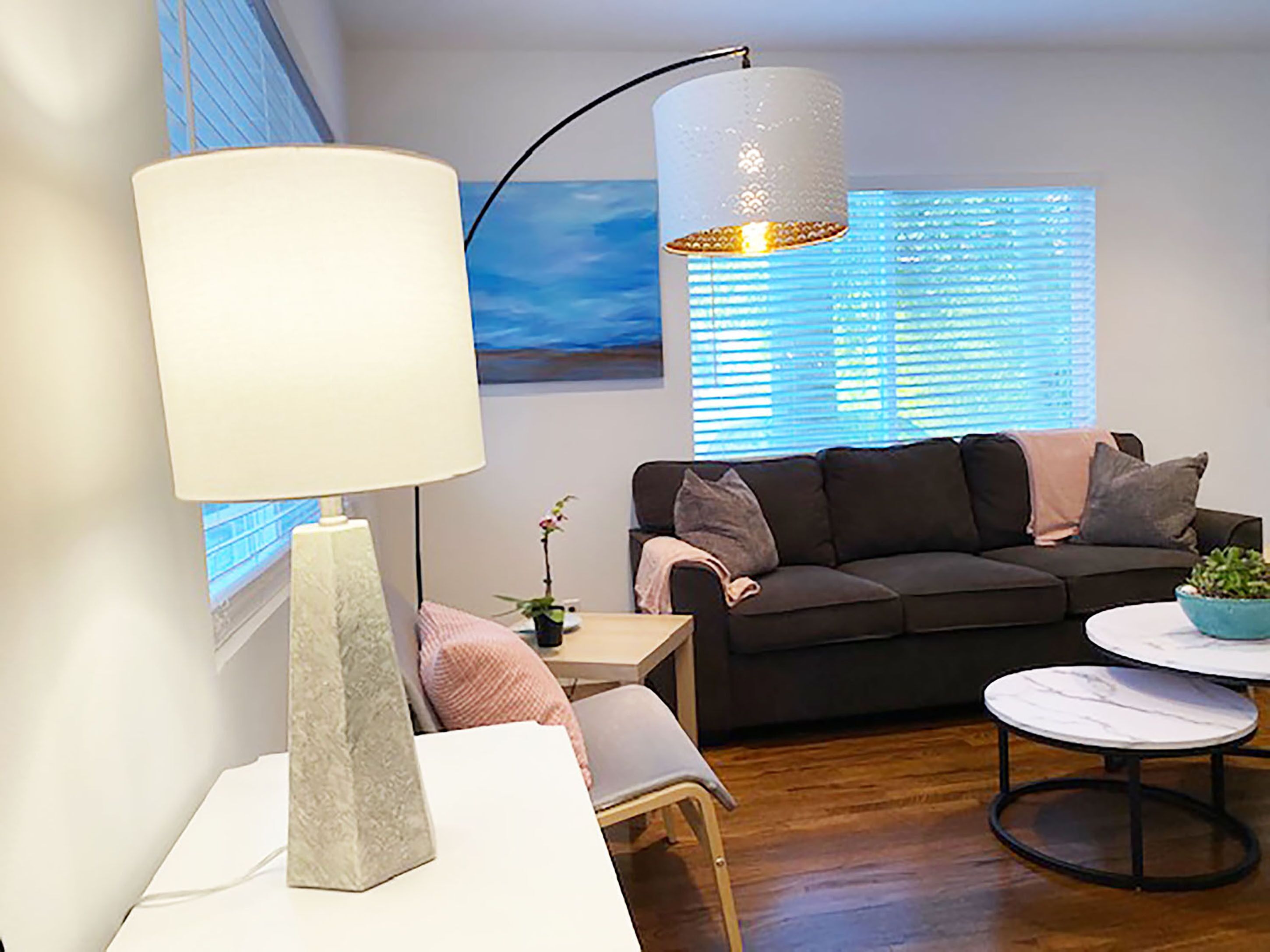 Un salon moderne avec un canapé, une table, une lampe et un luminaire suspendu.