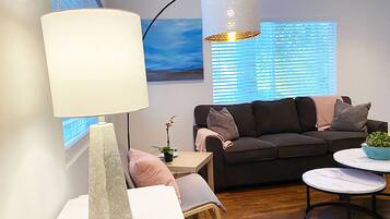 Un salon moderne avec un canapé, une table, une lampe et un luminaire suspendu.