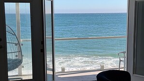 Une pièce dotée d’une grande porte vitrée donnant sur un balcon avec vue sur l’océan.