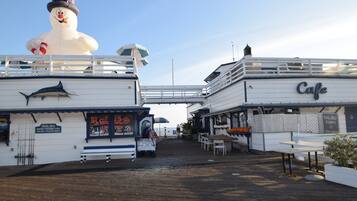 Un restaurant situé au bord de l’eau, agrémenté d’un grand bonhomme de neige décoratif, doté d’une terrasse et d’un panneau indiquant la direction du ponton de Malibu.