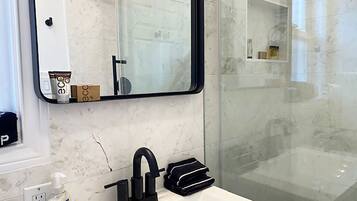 Une salle de bain avec un lavabo blanc, un robinet noir et un miroir au-dessus. Un flacon de savon liquide se trouve sur le côté gauche du lavabo.
