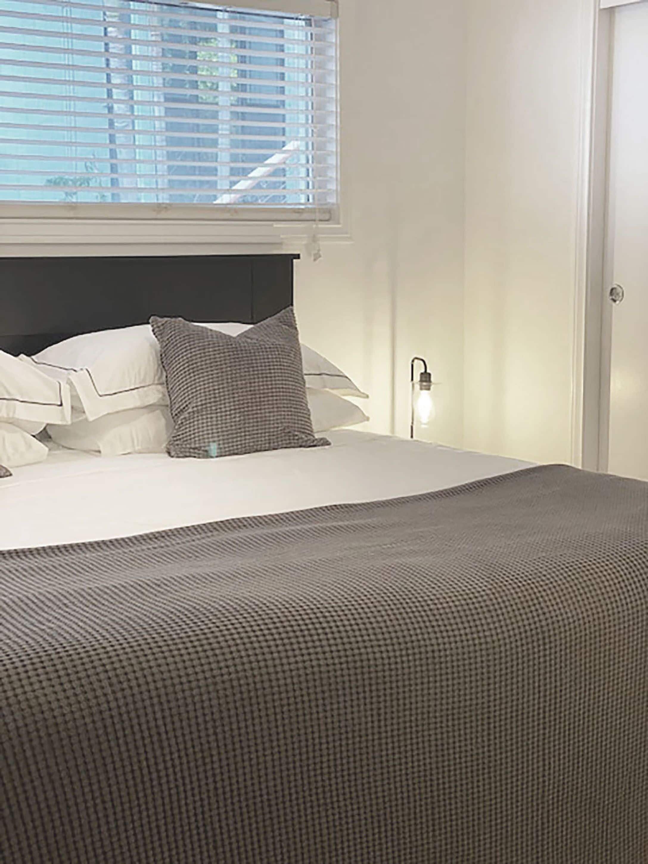A neatly made bed with a checkered blanket, white pillows, and a headboard.