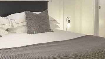 A neatly made bed with a checkered blanket, white pillows, and a headboard.