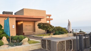 Un bâtiment moderne doté d’un toit plat, d’une entrée bien visible et offrant une vue sur la mer.