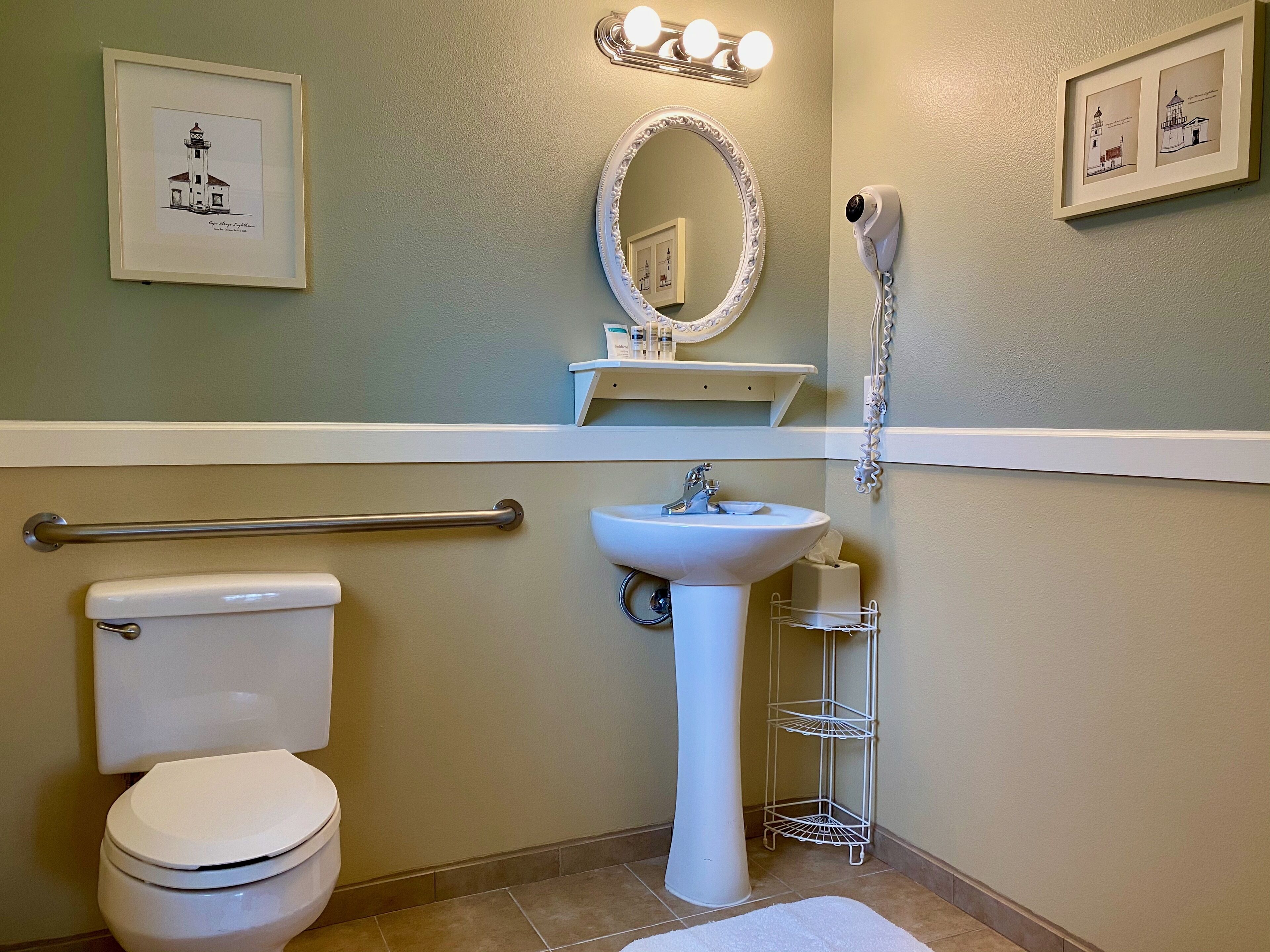 A bathroom with a toilet, sink, mirror, and a hairdryer mounted on the wall.