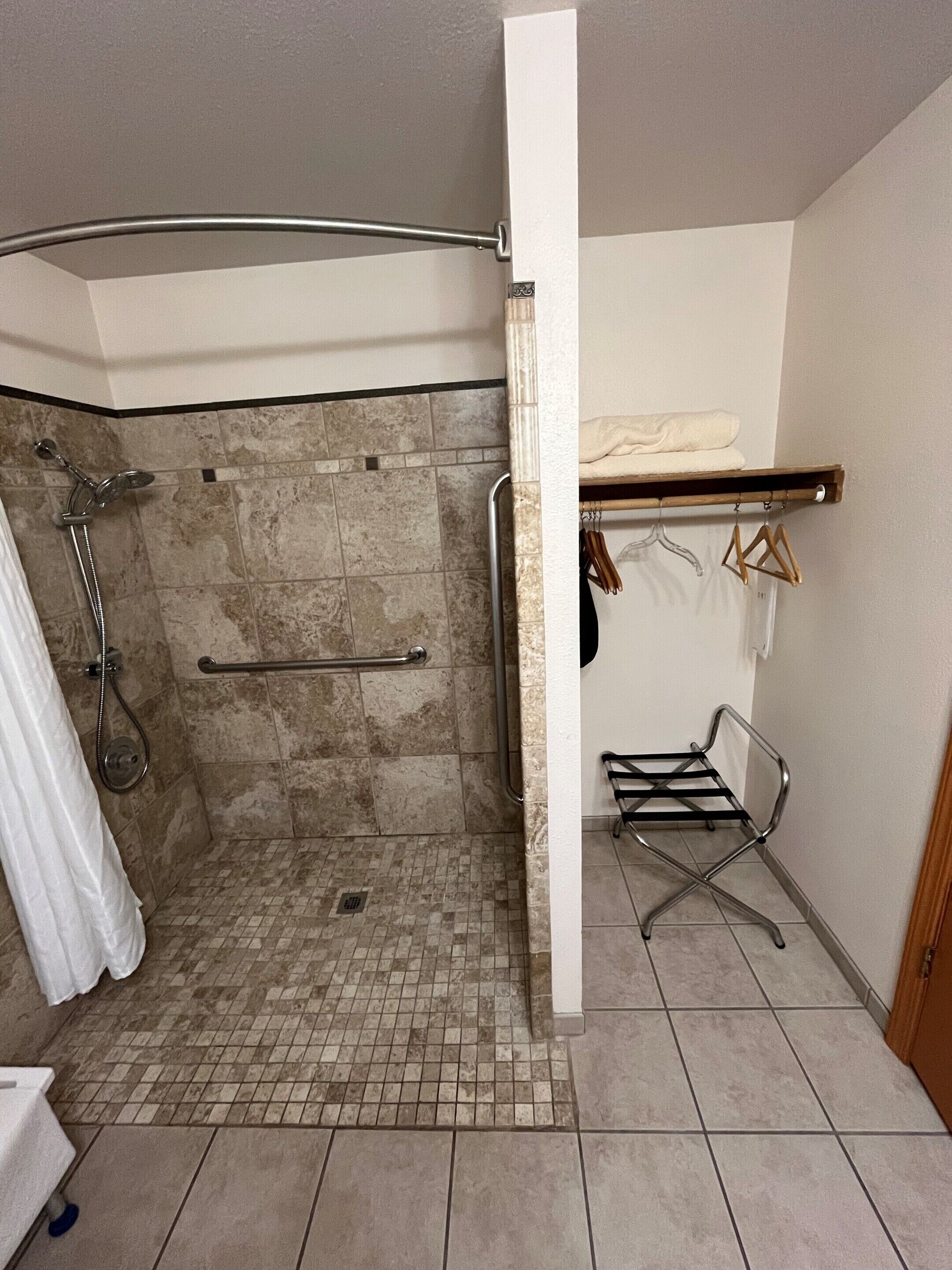 A bathroom with a shower, a towel rack, and a drying rack.