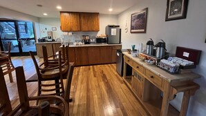 Una cocina moderna con armarios de madera, un comedor con sillas de madera y un refrigerador.