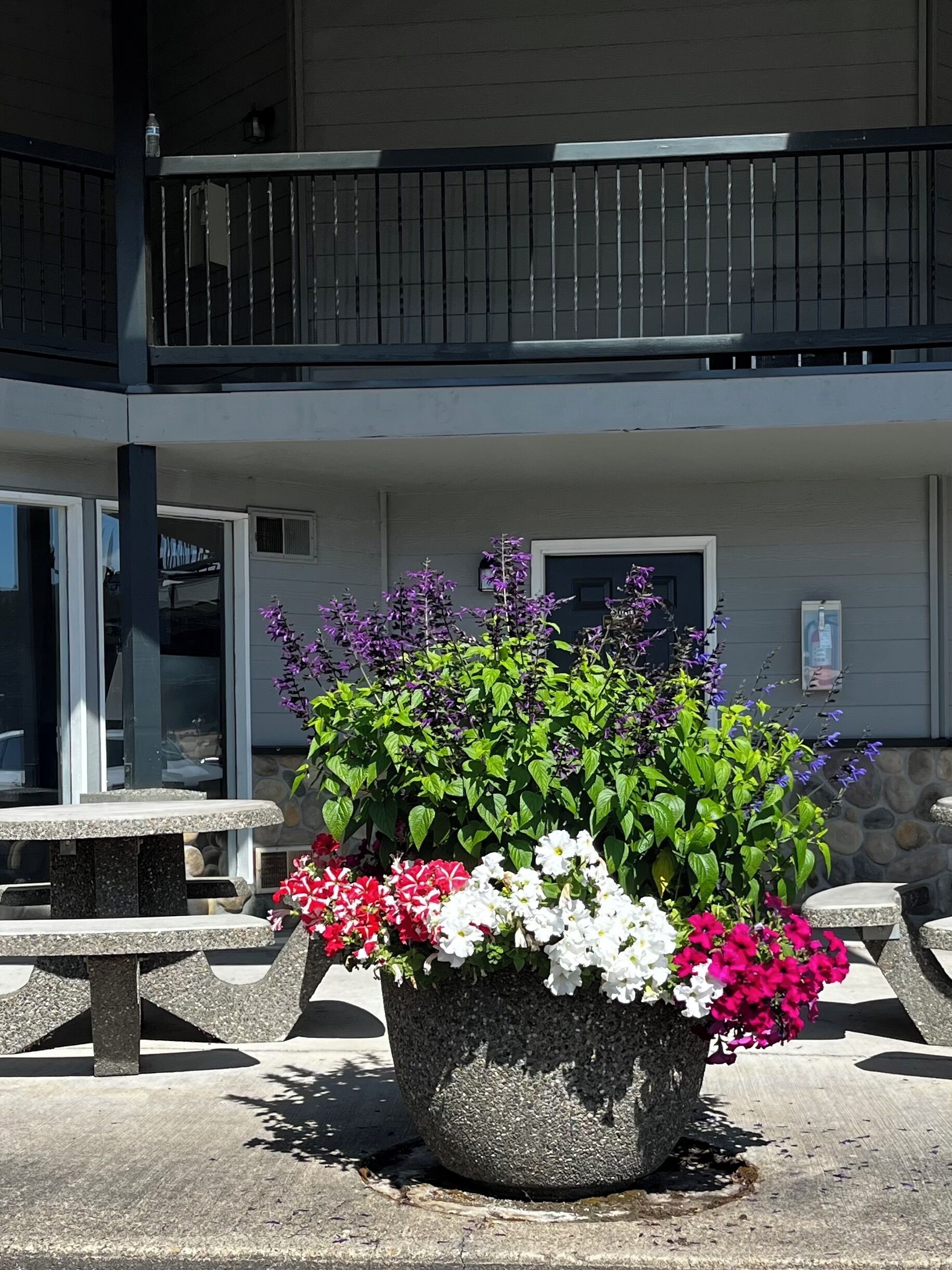 A building with a balcony, outdoor seating, and a flower planter.