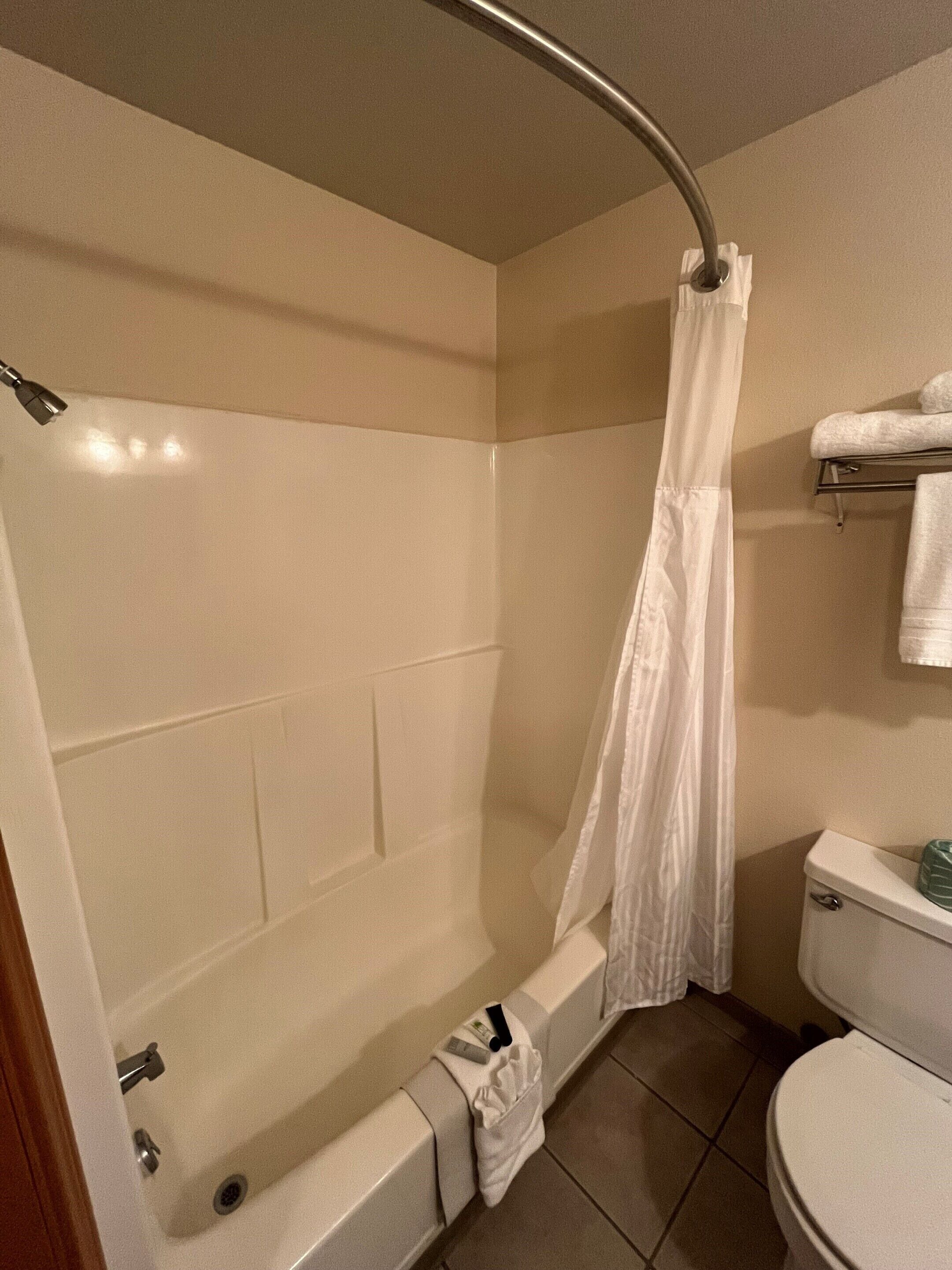 Une salle de bain avec une baignoire, des toilettes et un rideau de douche.