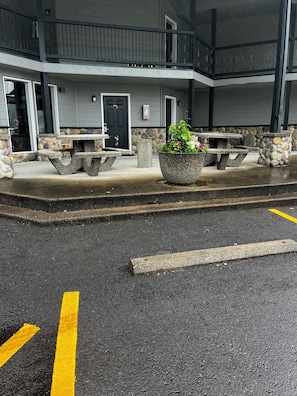 A building with a stone facade, a black door, and outdoor seating with a planter.